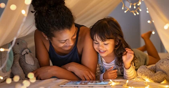 Woman and child reading together in fairytale tent.